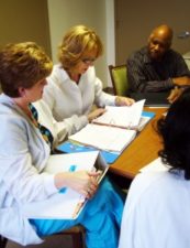 Healthcare Professionals gathered around a table reviewing paperwork.