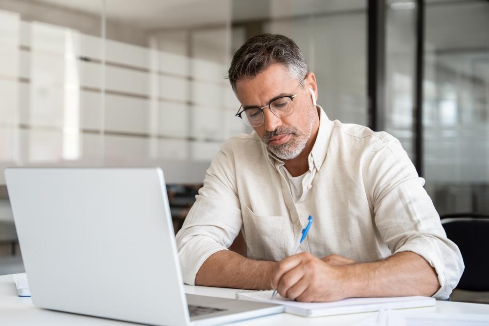 man-watching-webinar-taking-notes